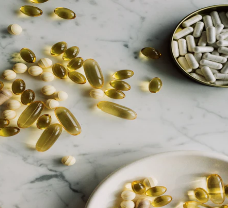 Hair vitamins scattered on a marble surface. Yellow capsules and grey capsules for hair growth.